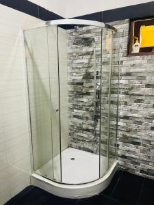 a glass shower in a bathroom with a stone wall at Dream villa in Imaduwa