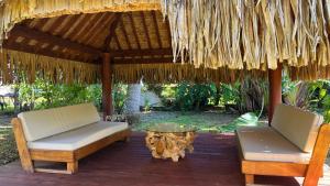 two chairs and a table under a straw umbrella at Moorea - Temae Reef Cottage in Temae