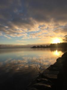 a view of a lake with the sun setting at Waters Edge Cottage in Alexandria +14 photos