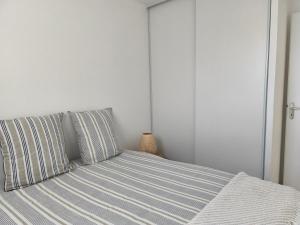 a bedroom with a bed with striped sheets and pillows at T2 L'orée du Golf labellisé 3 étoiles - Terasse et Parking in Pornic +14 photos