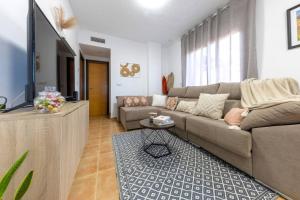 a living room with a couch and a tv at Collados Experience Piscina y Parking in Águilas