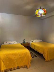 two beds in a room with yellow sheets at The Baron House in Tupiza