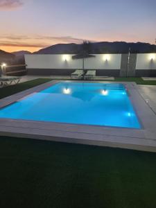 a large blue swimming pool in a backyard at night at Alojamiento GUADALENTIN in Pozo Alcón +5 photos