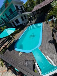 a blue swimming pool with two umbrellas next to a house at Pousada Mahara - Praia do Rosa in Imbituba