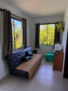 a bedroom with a couch and two large windows at Pousada Mahara - Praia do Rosa in Imbituba +23 photos