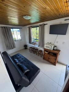 a living room with a black leather couch and a table at Pousada Mahara - Praia do Rosa in Imbituba