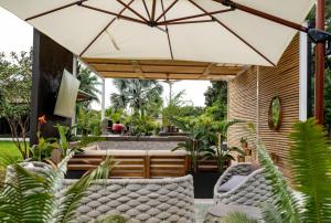 an outdoor patio with chairs and an umbrella at Romantic Guest House · Heated Spa & Pool · Private Retreat in Fort Lauderdale