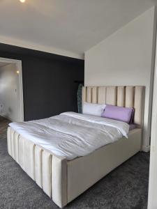 a bedroom with a large white bed with purple pillows at Glams luxury home in Wolverhampton