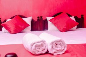 a bed with red and white pillows and towels at Shrine Inn in Kandy