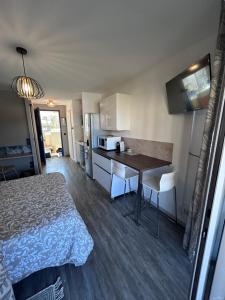 a bedroom with a bed and a table and a kitchen at Studio zen climatisé piscine parking in Balaruc-les-Bains