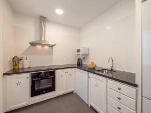 a kitchen with white cabinets and a sink at Casa Major by 3VILLAS in Fornells