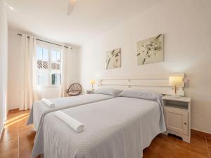 a white bedroom with two beds and a window at Casa Major by 3VILLAS in Fornells