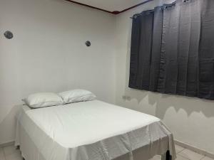 a white bed in a room with black curtains at Hostel Treebu in Valladolid