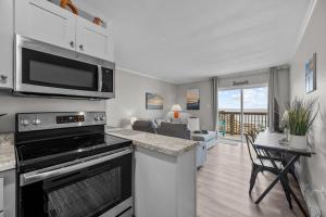 a kitchen with a microwave and a living room at Feel the Sea Breezes in North Topsail Beach