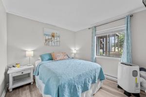 a white bedroom with a bed and a window at Feel the Sea Breezes in North Topsail Beach