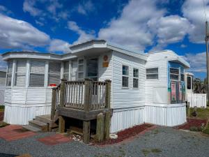 a white house with a wooden porch in front of it at The Salty Camper in North Topsail Beach