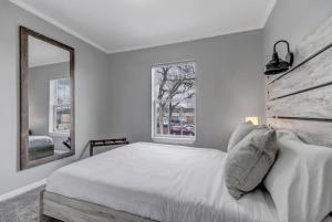 a white bedroom with a bed and a mirror at Denver Retreat in Arvada