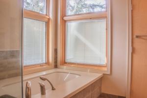 a bathroom with a bath tub and two windows at Quiet Private Room with Ensuite Free Parking in Victoria