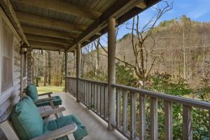a porch with chairs and a view of the woods at Townsend Charm: River View Historic Log Cabin! in Townsend