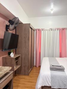 a bedroom with a bed and a flat screen tv at Sunvida Tower Corner Suite Across SM Cebu in Cebu City