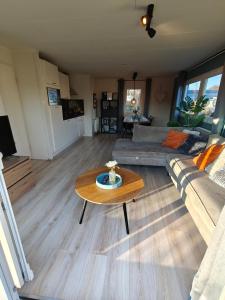 a living room with a couch and a table at Het Dobbertje, charmant houten huisje in Sint Maartensvlotbrug