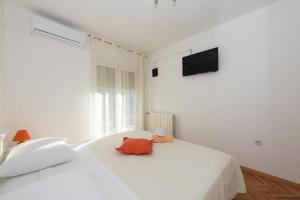 a white bedroom with a large white bed and a television at Room Peričić in Strožanac