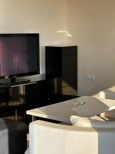 a living room with a tv and a white table at Villa 11 Infinity pool & garden in Dobra Voda +34 photos