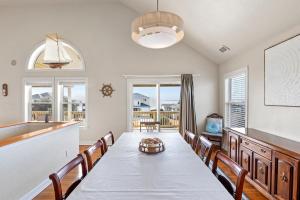 a dining room with a table and chairs and a kitchen at Sounds Like A Plan in Kill Devil Hills