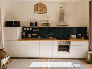 a kitchen with white cabinets and a stove top oven at Chez flader, deux pièces de 55m2 centre historique in Langeac