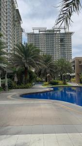 a large swimming pool with palm trees and buildings at Meraki Urban in Davao City
