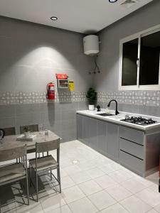 a kitchen with a counter and a sink and a table at شقة اند هوم in Hail