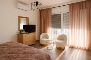 a bedroom with a bed and two chairs and a television at Theologos Residencies in Theologos