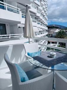a balcony with a glass table and an umbrella at Blue Ocean Costa Adeje 502 in Playa de las Americas