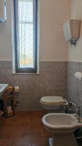 a bathroom with a toilet and a sink and a window at Casa Algherini in Borghetto