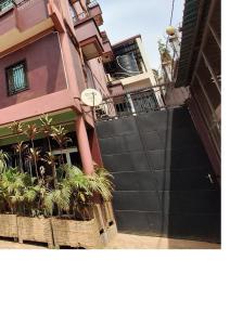 a building with a black gate and some plants at Ngueye Hotel in Yaoundé