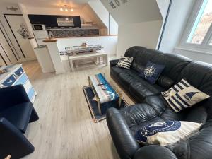a living room with a leather couch and a table at Les Roitelets "MARINE" Appartement T4 Duplex 80m2 - Thème Marin - Entièrement NEUF - Classé 3 étoiles - Proche Centre-ville & Thermes - Tout Confort - Ménage et Linge de maison INCLUS in La Bourboule