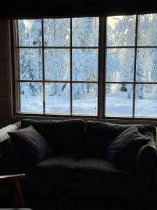 a couch in front of a window with snow at Ailo Iso-Syöte in Pudasjärvi