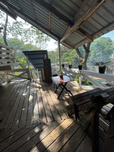 a wooden deck with a bench and a chair on it at Kuyas Tree House in Puerto Princesa City