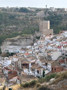 a group of white buildings on a hill with a castle at Casa Cueva Toni in Alcalá del Júcar