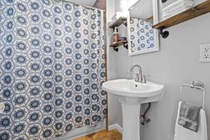 a bathroom with a sink and a blue and white shower curtain at Waldo Craftsman - Fenced yard Walkable to dining in Kansas City +32 photos