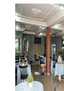 a dining room with tables and chairs and a man sitting at at Ngueye Hotel in Yaoundé
