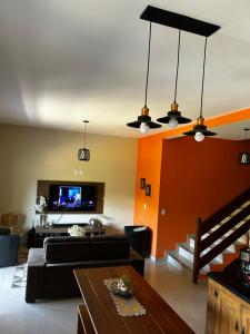 a living room with a couch and a tv at Pousada Acordes do Lago in Cunha