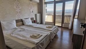 a bedroom with two beds and a large window at Хотел Магура in Rabisha