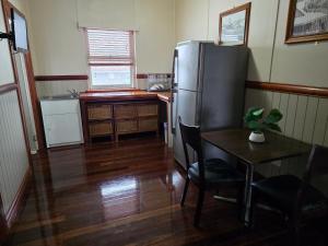 a kitchen with a table and a refrigerator and a table and chair at The Gympie Empire in Gympie