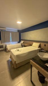 ein Hotelzimmer mit zwei Betten und einem Waschbecken in der Unterkunft Hotel Coroados Foz Express in Foz do Iguaçu