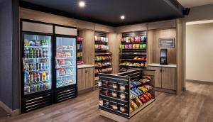 a grocery store aisle with multiple refrigerators and drinks at Hyatt Studios Texarkana in Texarkana