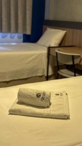 Ein Stapel Handtücher auf einem Bett in einem Hotelzimmer in der Unterkunft Hotel Coroados Foz Express in Foz do Iguaçu