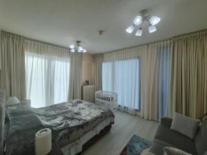 a bedroom with a bed and a crib and windows at Belstay2 in Ras al Khaimah
