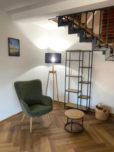 a living room with a green chair and a staircase at Białe Żagle Mazury in Węgorzewo