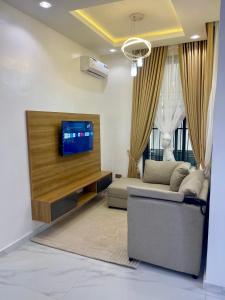 a living room with a couch and a flat screen tv at Luxury Four Bedroom Duplex in Asokoro Abuja in a Secure Estate with Fast WiFi & 24hours Electricity in Asokoro